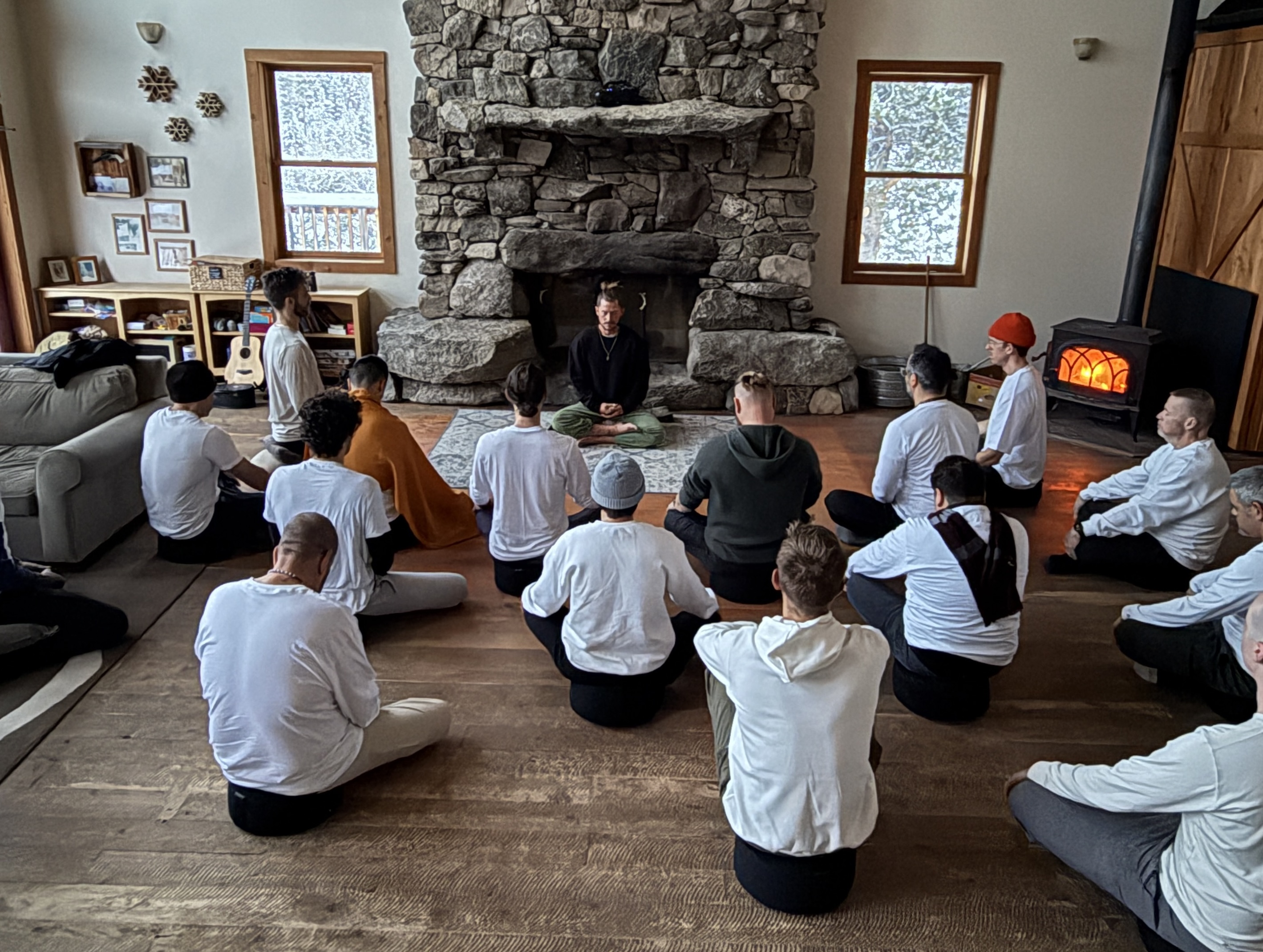 Men gathered in a sharing circle around a stone fireplace at a winter retreat