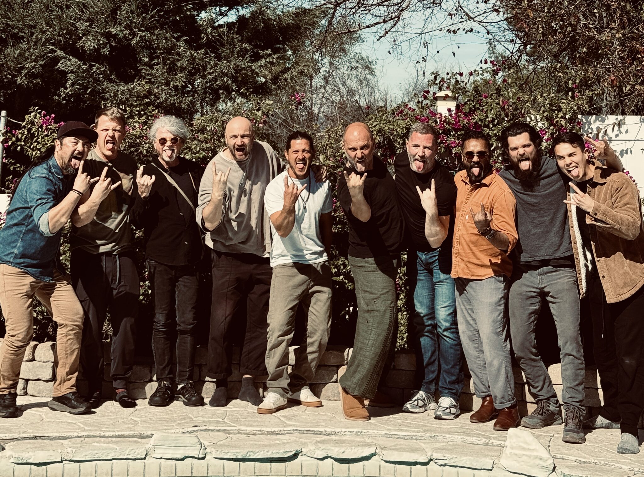 Eleven men lined up, laughing, pulling faces for the camera